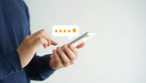Male customer's hand pressing on smartphone screen with five-star rating - close up on customer man hand pressing on smartphone screen with  five star rating feedback icon and press level good rank for giving best score point to review the service , technology business concept - Above The Bar - close up on customer man hand pressing on smartphone screen with  five star rating feedback icon and press level good rank for giving best score point to review the service , technology business concept - Above The Bar
